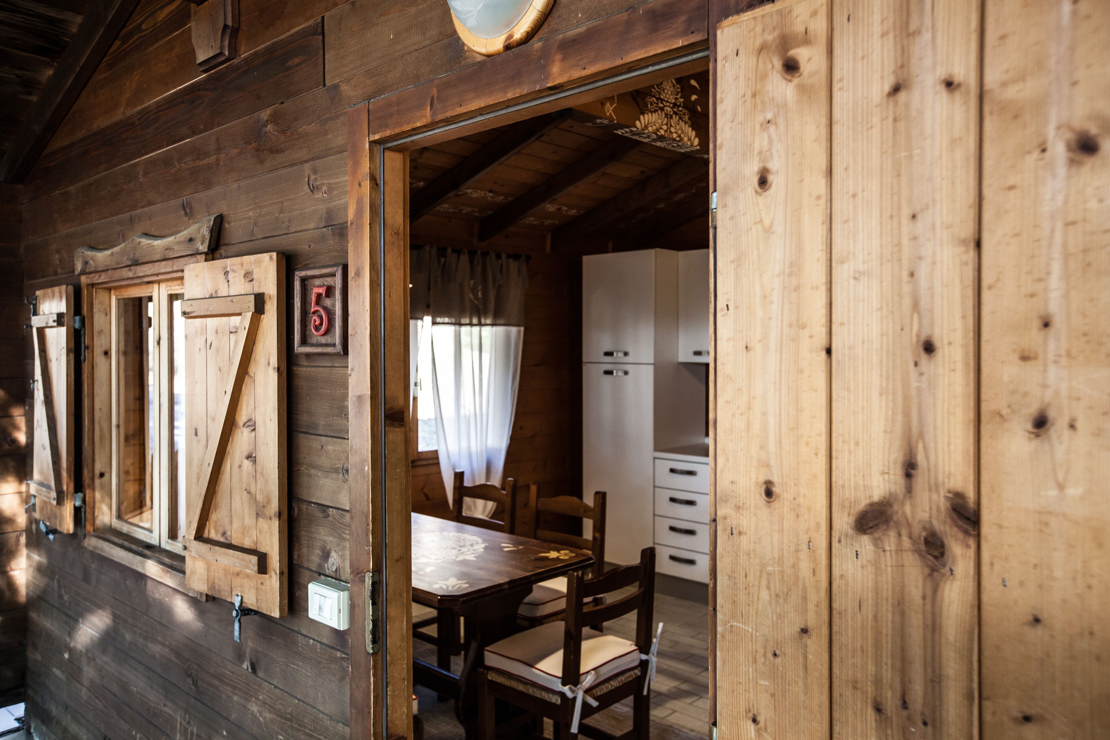 Een houten cabinestijl interieur met een eethoek, een keuken en een bord met het cijfer '5' aan de muur.