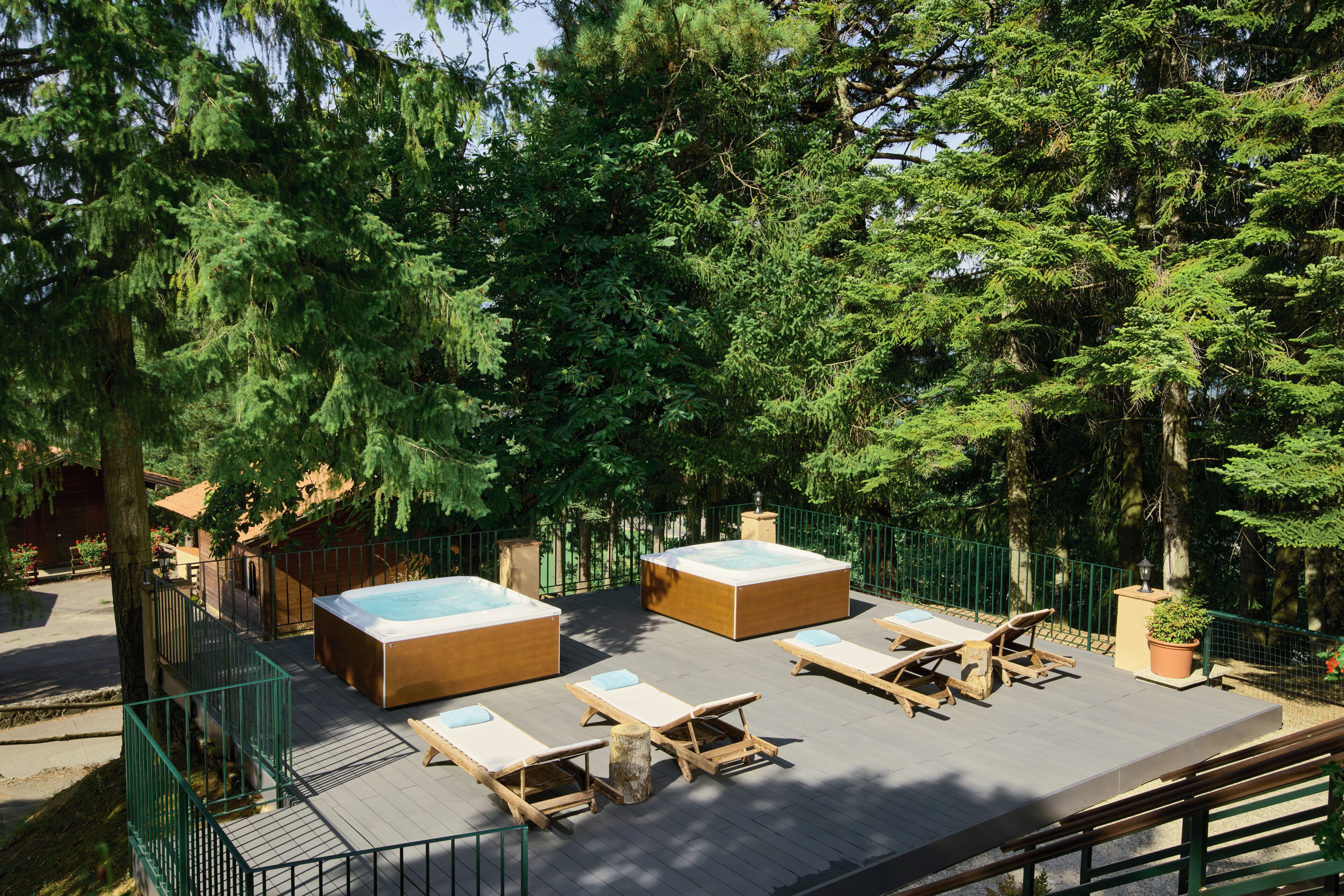 Eine Dachterrasse mit Whirlpools, Liegestühlen und einer Holzterrasse.
