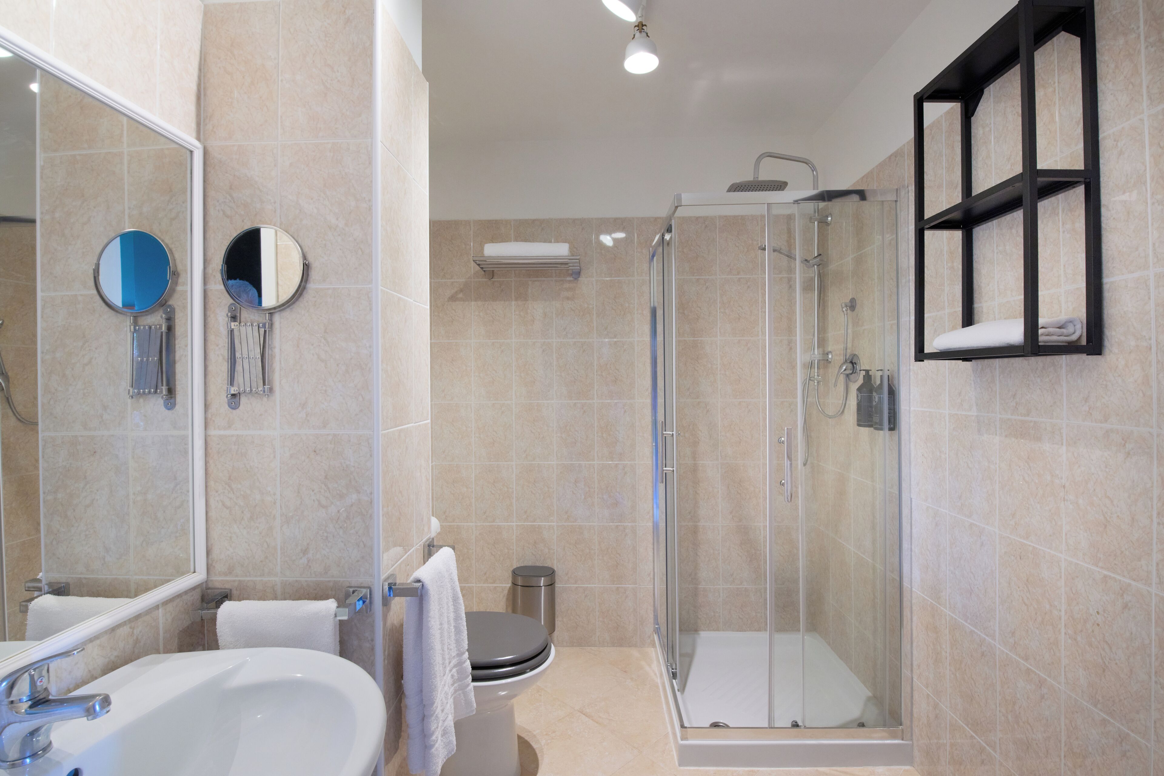 Une salle de bain moderne avec une douche à parois de verre, un lavabo, des toilettes et un miroir.