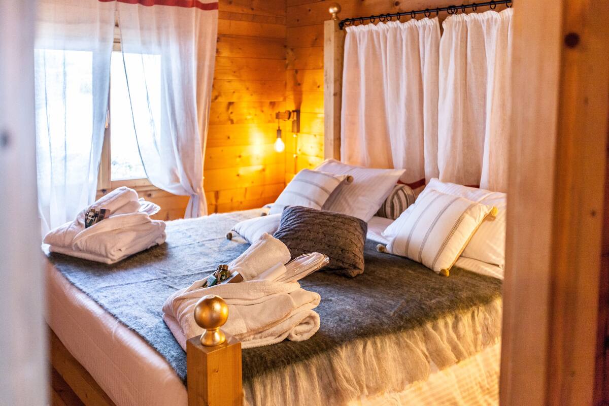 A wooden cabin bedroom with a bed, towels, and a nightstand.