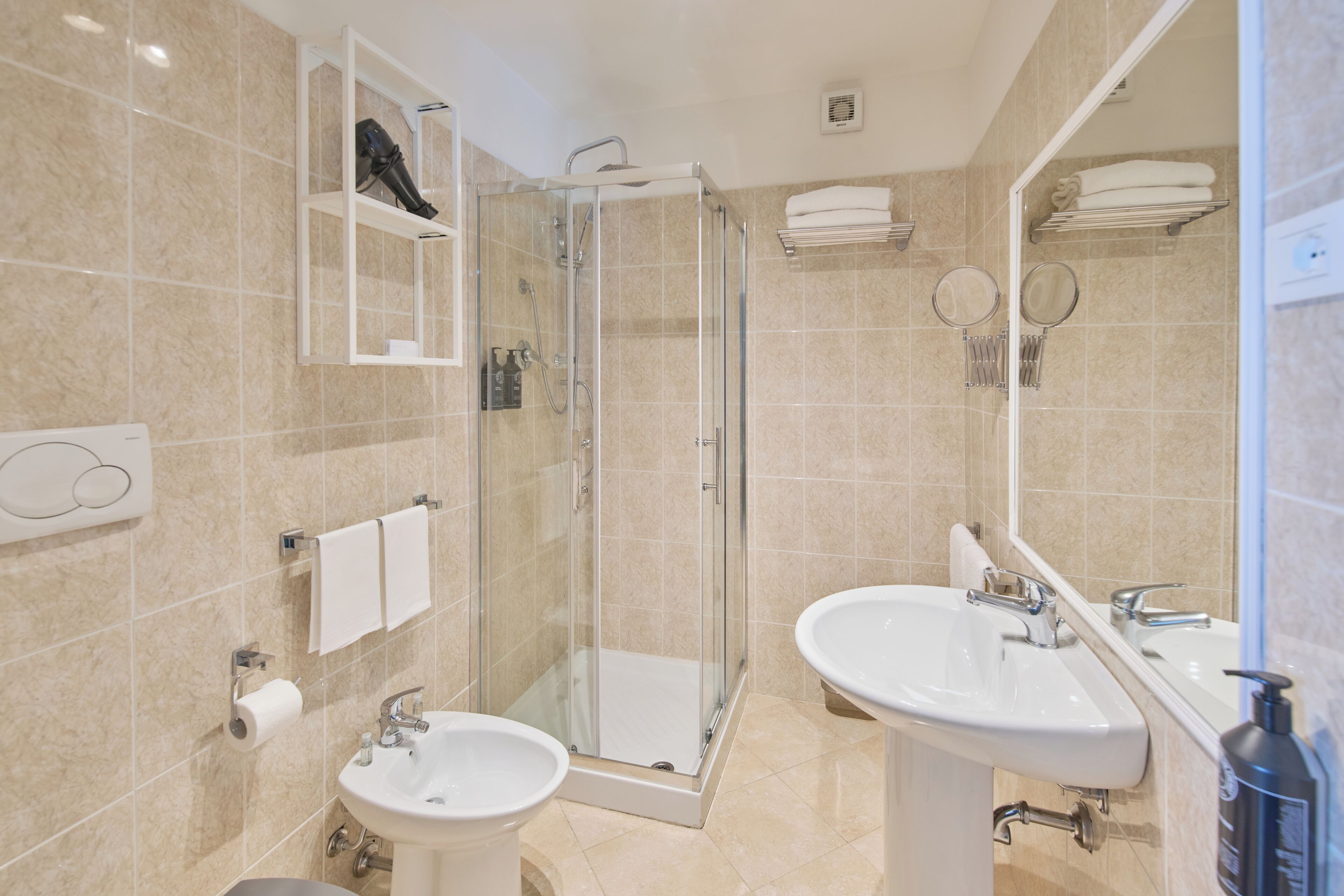 A modern bathroom with a glass-enclosed shower, two sinks, and a mirror.