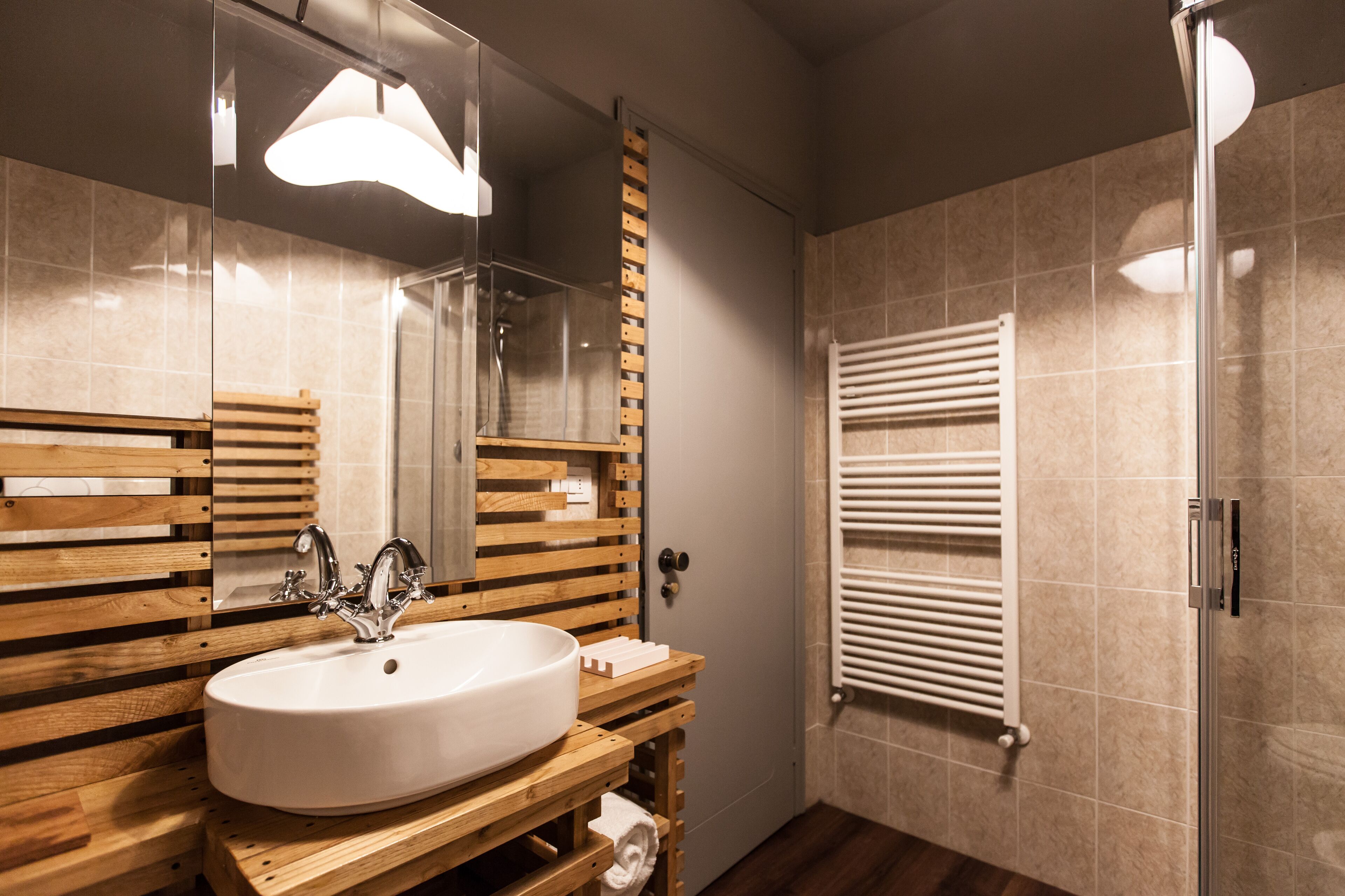 Un baño moderno con tocador de madera, un lavabo grande, un espejo y cabina de ducha de vidrio.