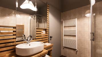 Un baño moderno con tocador de madera, un lavabo grande, un espejo y cabina de ducha de vidrio.