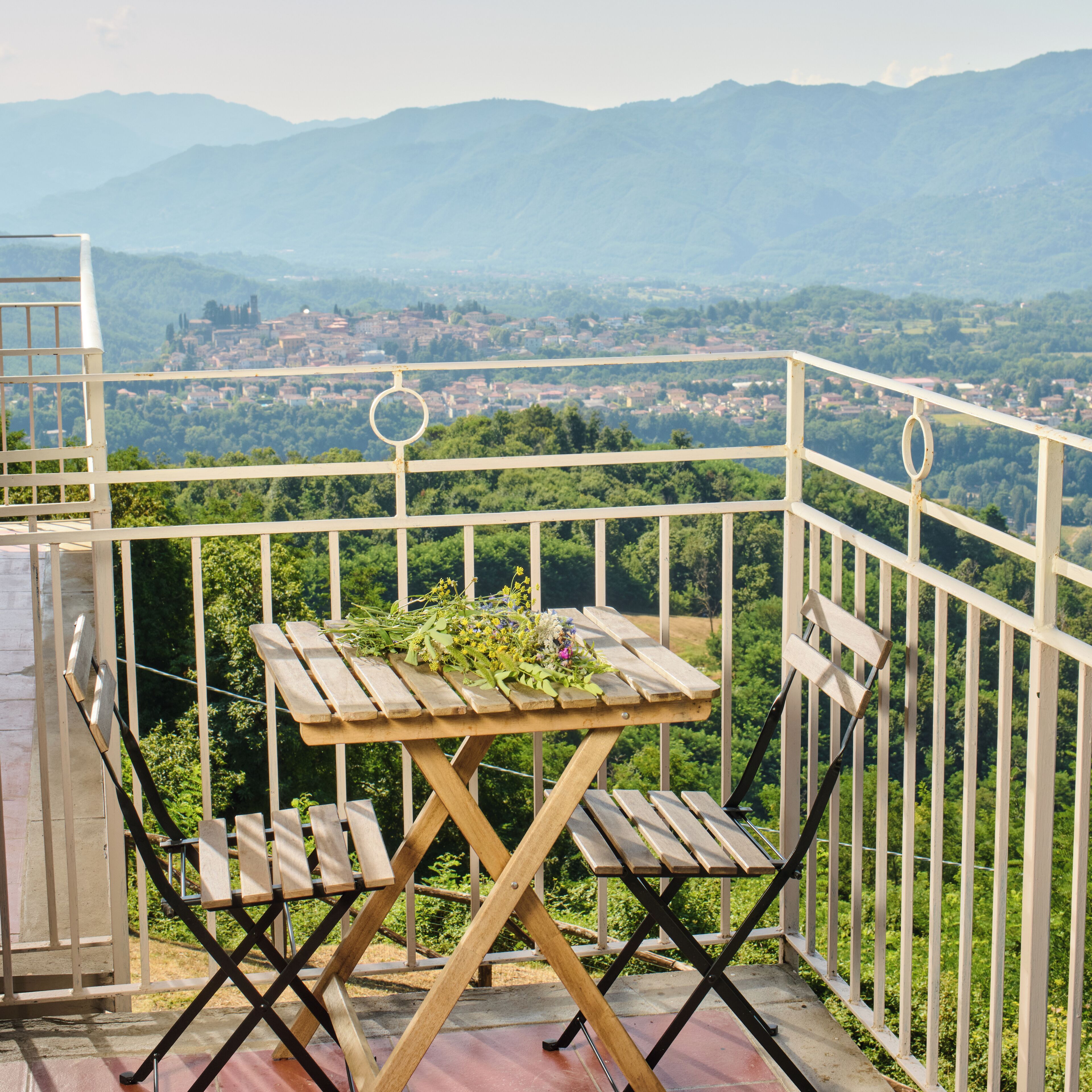 A wooden table with a view of a town and mountains in the background.