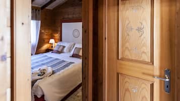 Een houten slaapkamer met een bed, kussens, een nachtkastje, een lamp en een handdoek op de vloer.