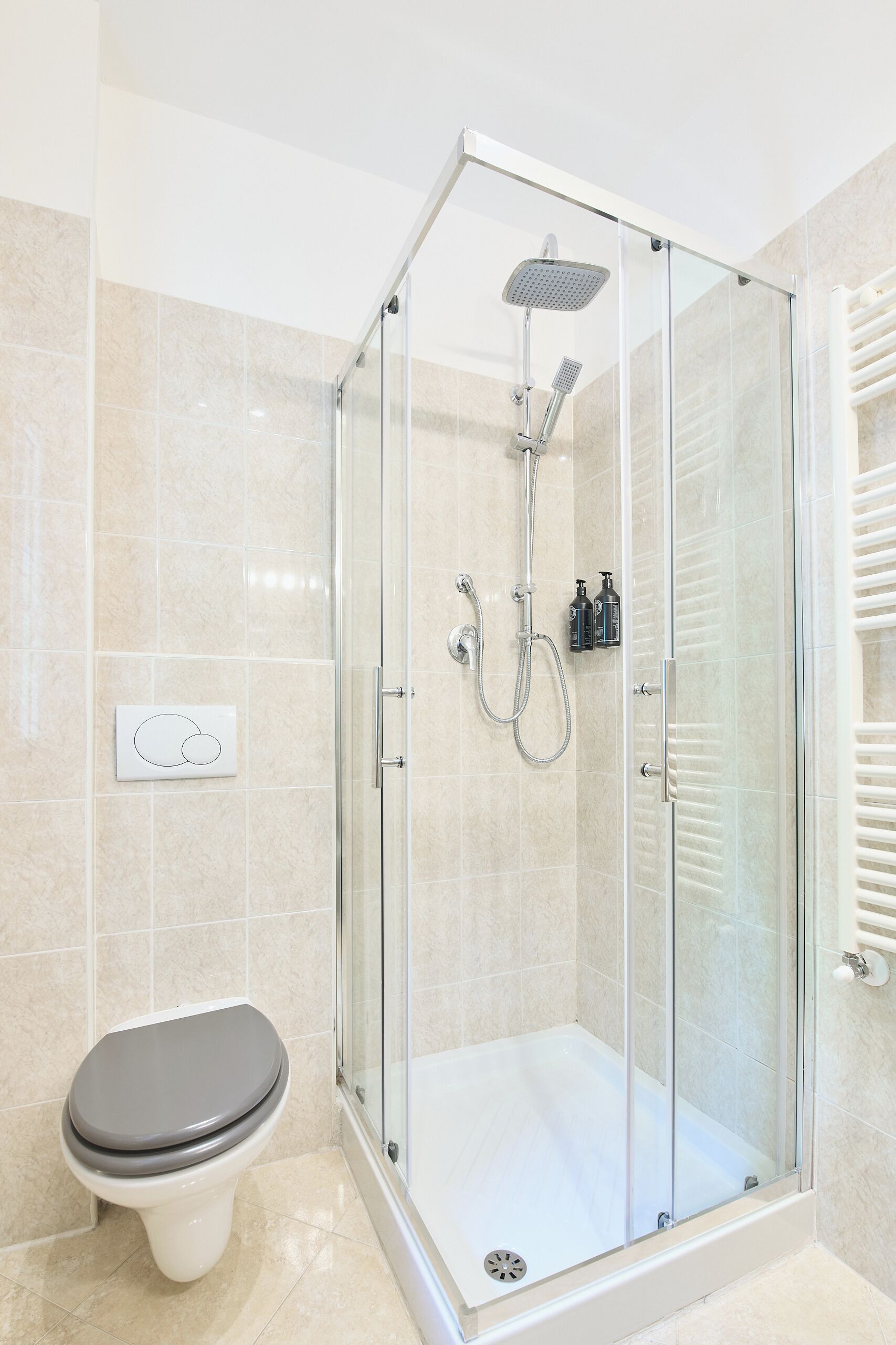 Un baño moderno con ducha de vidrio, inodoro y perchero para toallas.
