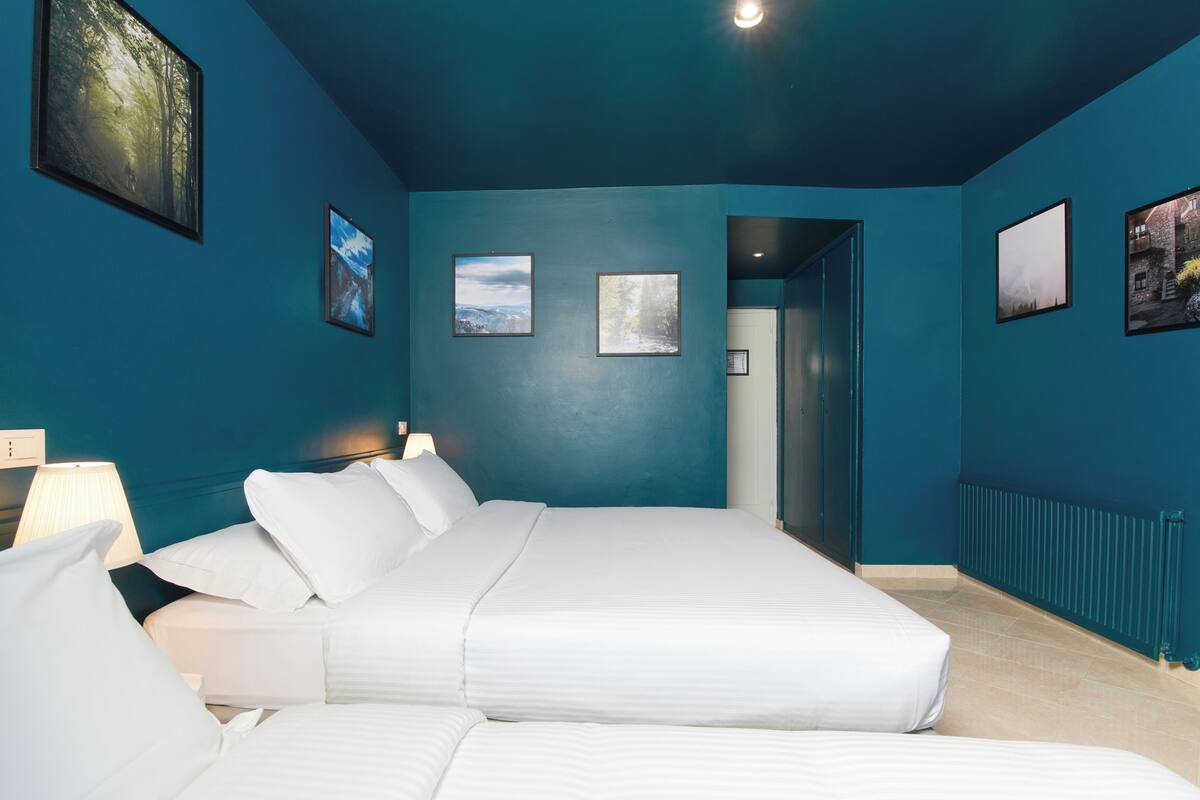 A bedroom with a large bed, a nightstand, and a wall-mounted lamp.