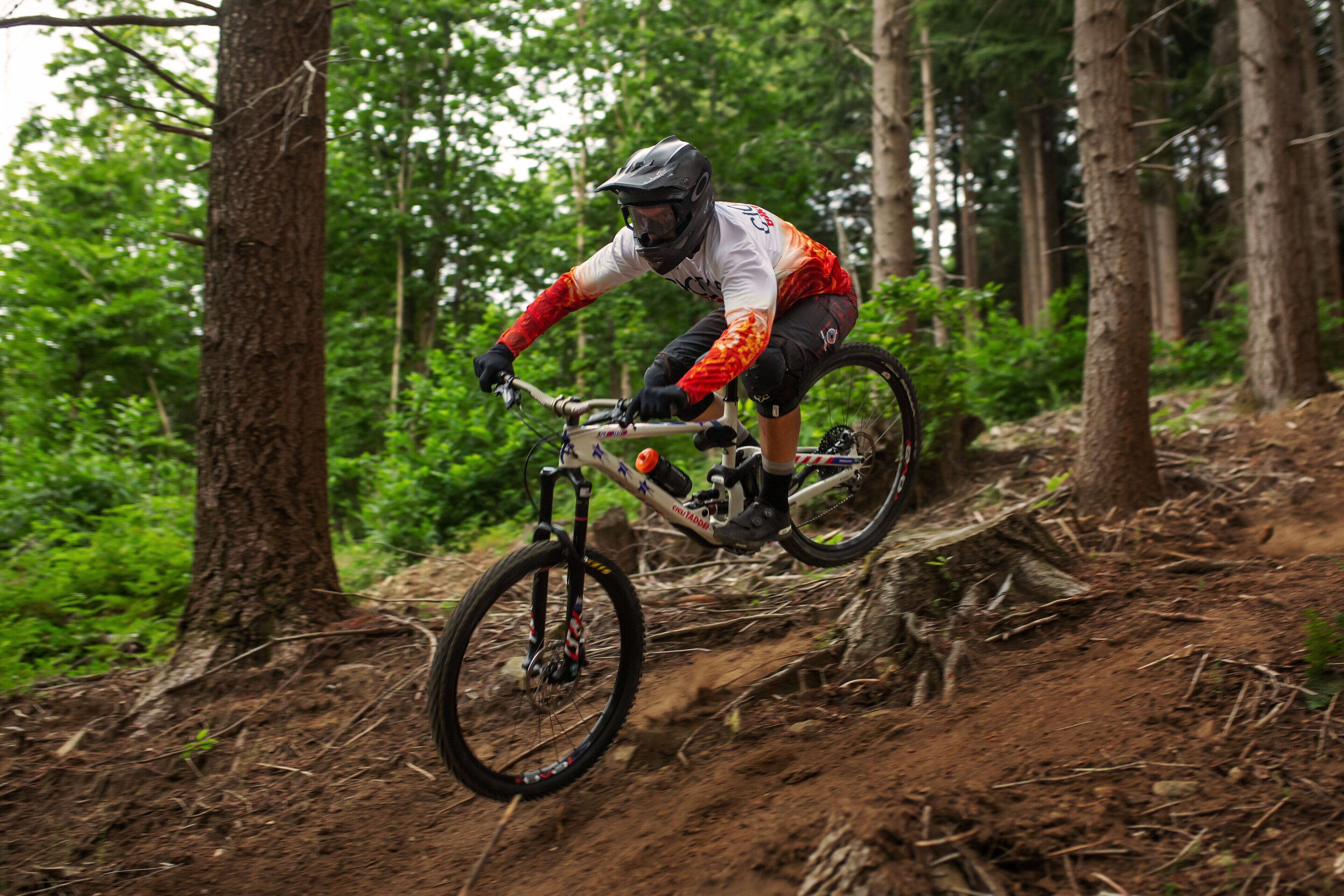 A mountain biker on a trail surrounded by trees.