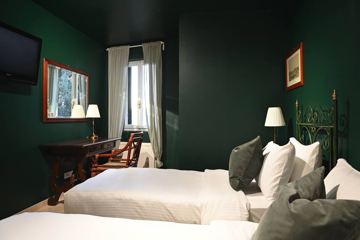 A hotel room with two beds, a desk, a chair, and a television.