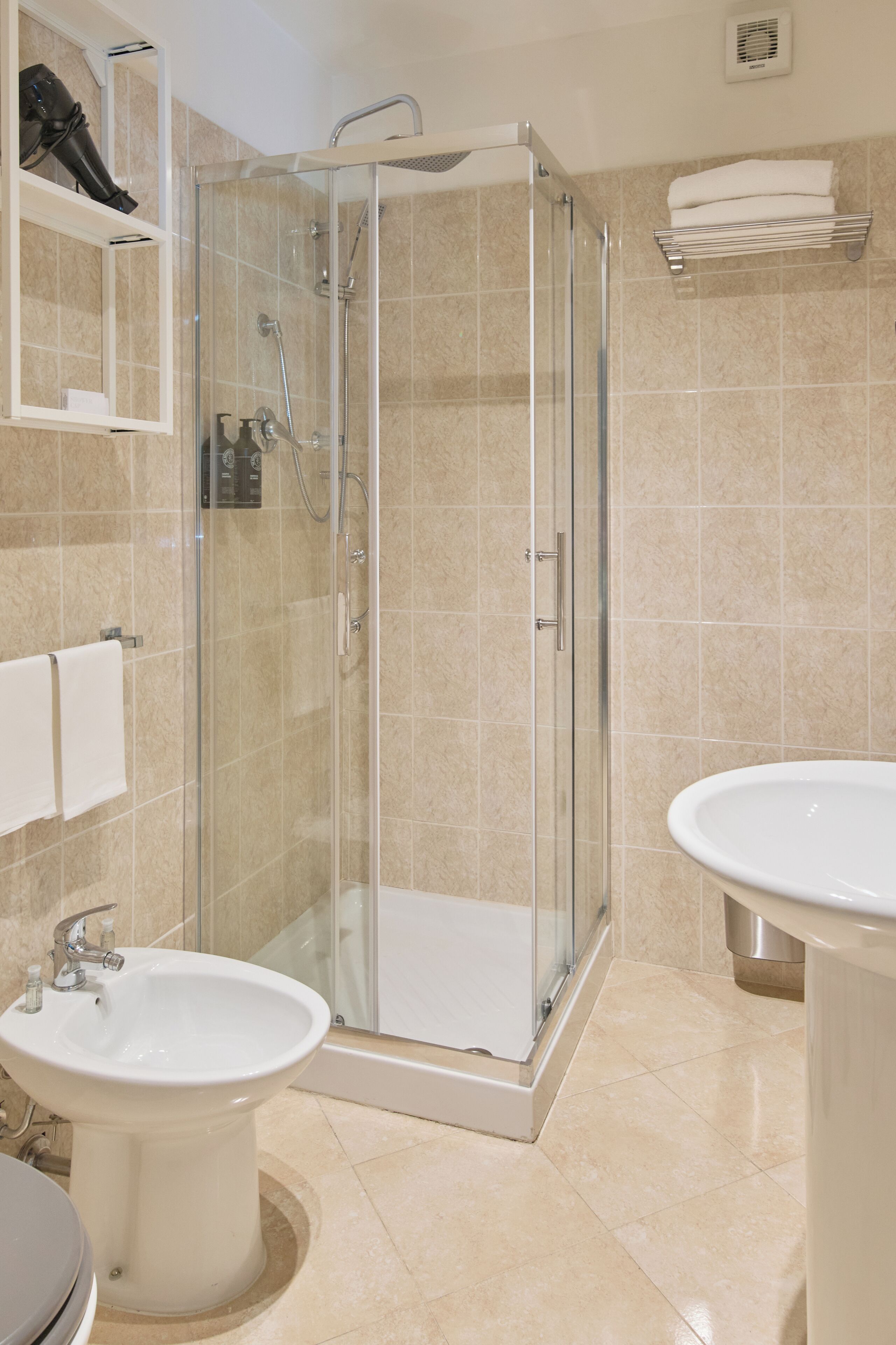 Un bagno moderno con doccia vetrata, due lavabi e un porta asciugamani.