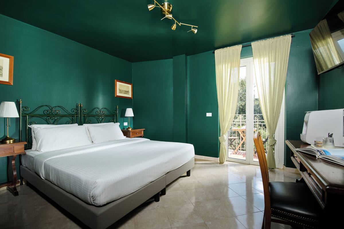 A bedroom with a bed, bedside tables, a desk, and a chair.