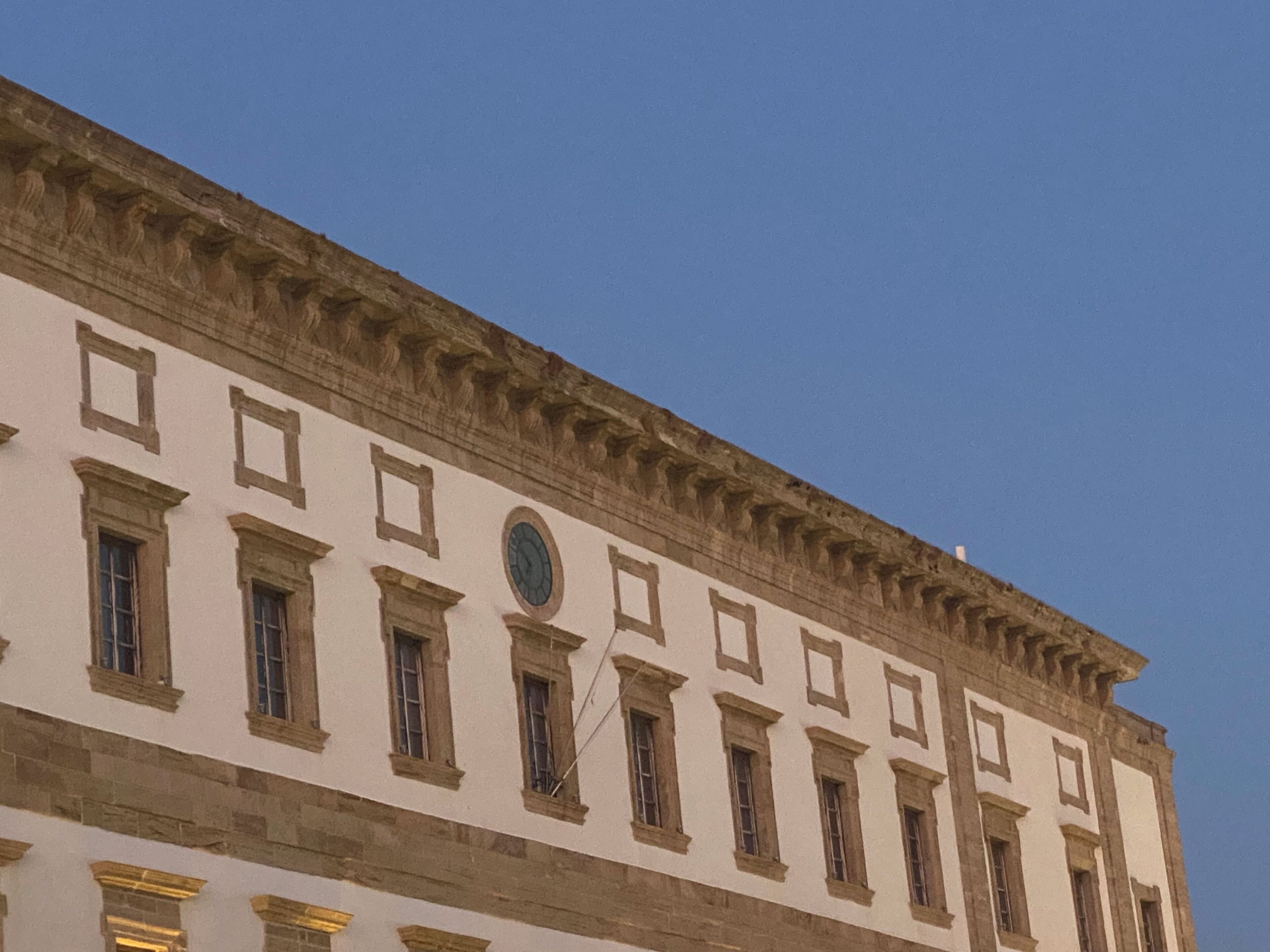 A building with a classical architectural style, featuring a symmetrical facade with evenly spaced windows and a central circular window.