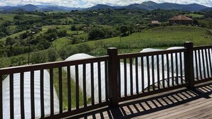 A wooden deck with a view of a green landscape and mountains.