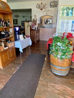 Zona de bar con estanterías de madera, un jukebox y una gran maceta de barril con flores.