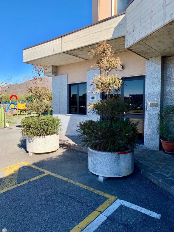 A building with a concrete facade, a large entrance, and potted plants in front.