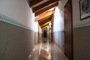 Un pasillo con pisos de baldosas, vigas de madera y puertas a ambos lados.