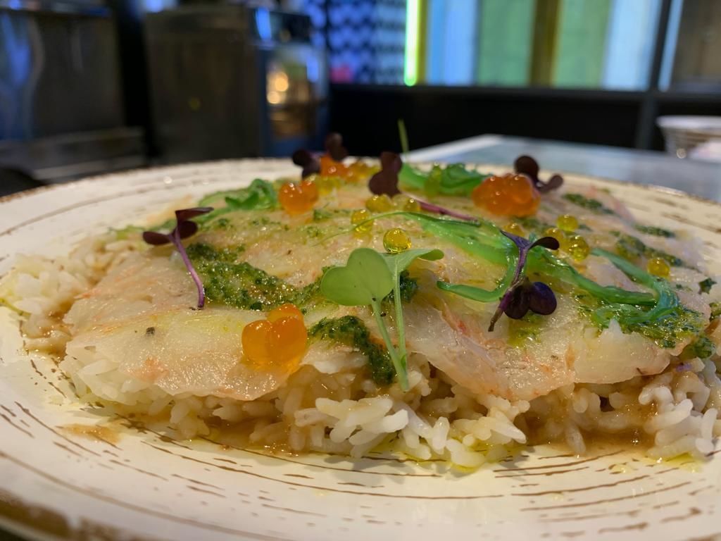 Ein Teller Essen mit Reis und Fisch, garniert mit Grünzeug und essbaren Blüten.