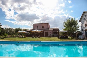 A swimming pool with a building in the background. - Sicily Country House & Beach (Catania)
