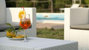 Un vaso de jugo de naranja con una rodaja de naranja y una pajita sobre una mesa junto a una piscina.