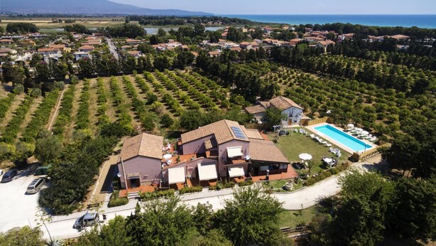 Zona residencial con una casa grande que cuenta con piscina y paneles solares, rodeada de exuberante vegetación y vistas a la montaña y al mar.