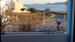 A coastal view with buildings, a road, and a body of water. - Tommy's Rooms (Rhodes)
