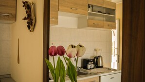 A kitchen with wooden cabinets, a coffee maker, and a vase with tulips. - Tommy's Rooms (Rhodes)