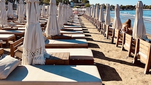 A beachside resort with rows of wooden loungers and white umbrellas, offering a view of the sea. - Kalia Beach Hotel Side  (Manavgat)