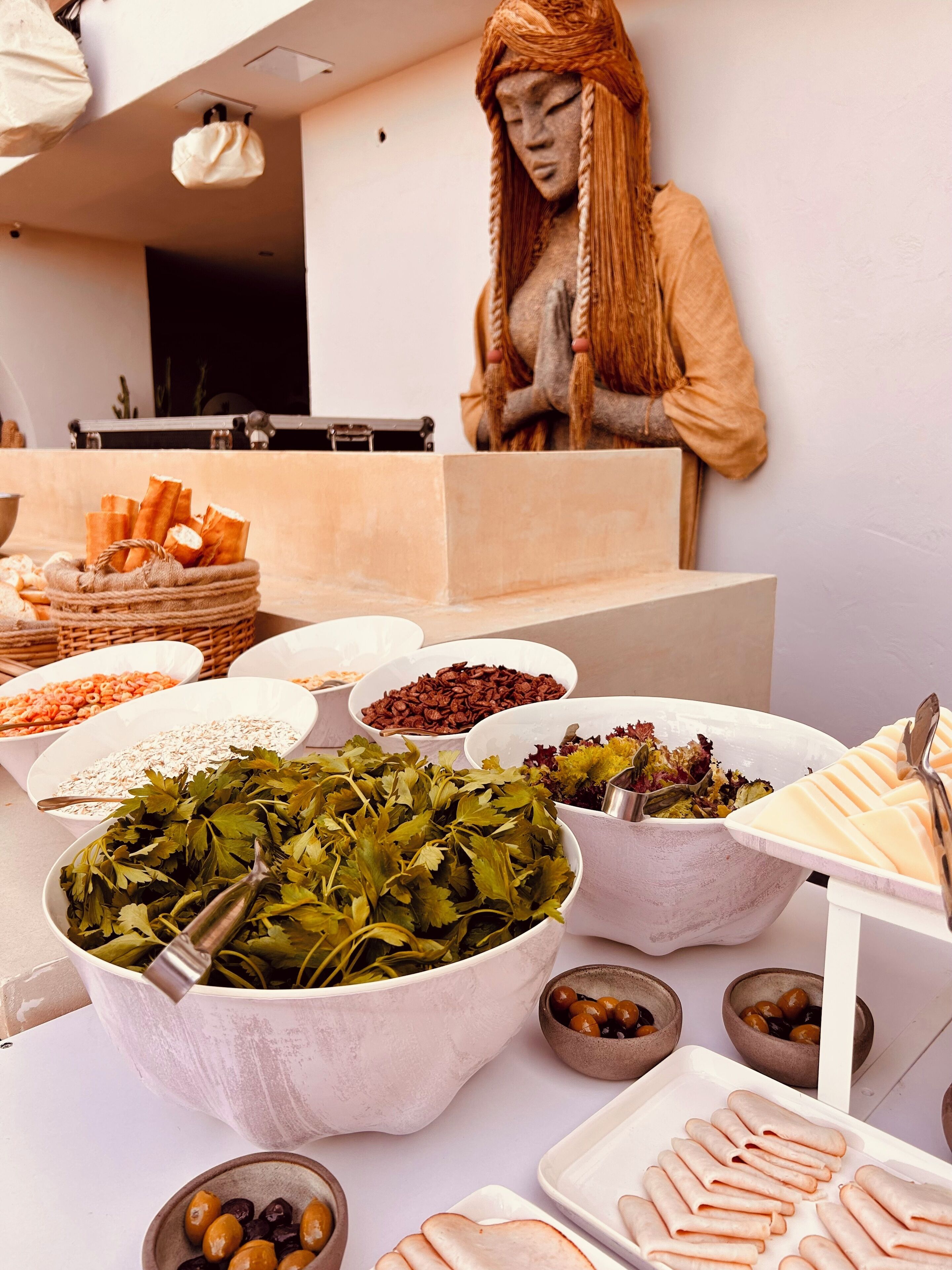 Un buffet proposant une variété d’aliments, notamment du pain, des olives et des légumes verts.
