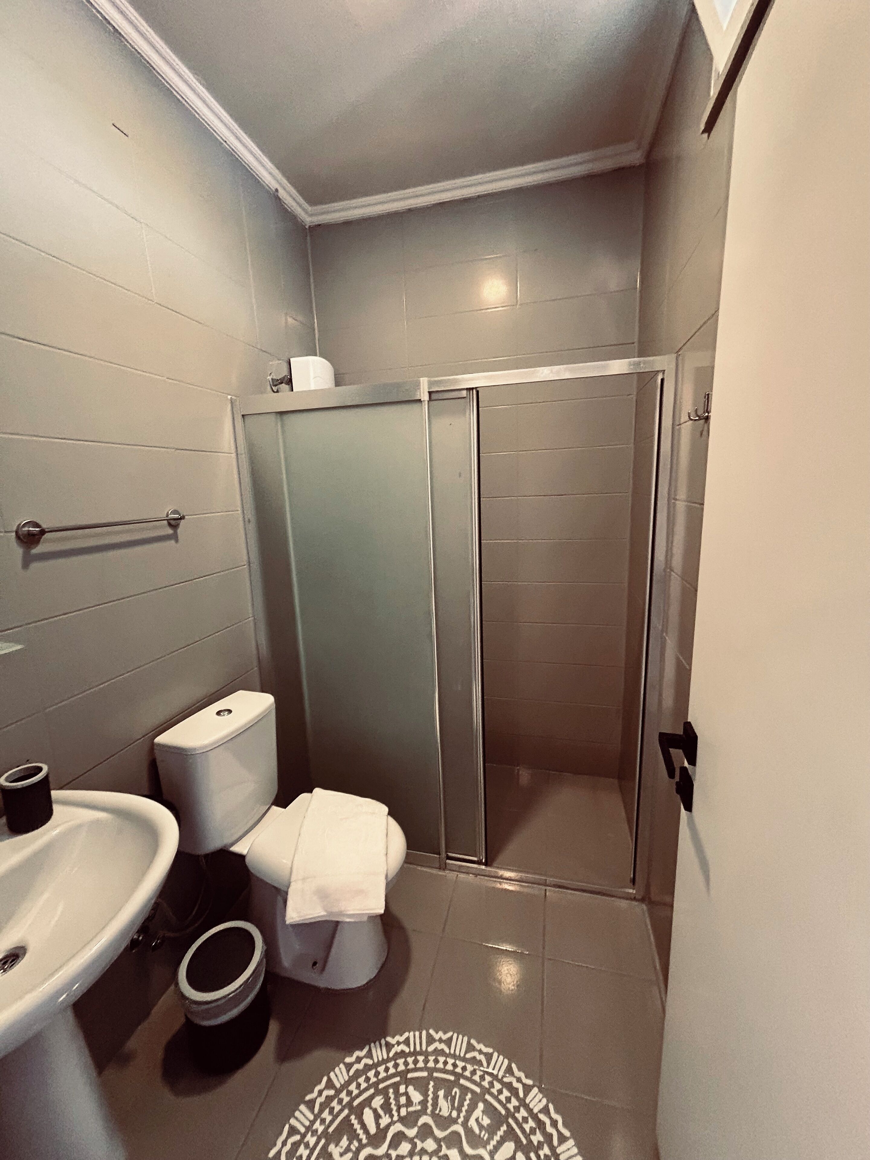 Et badeværelse med toilet, vask og brusebad.
