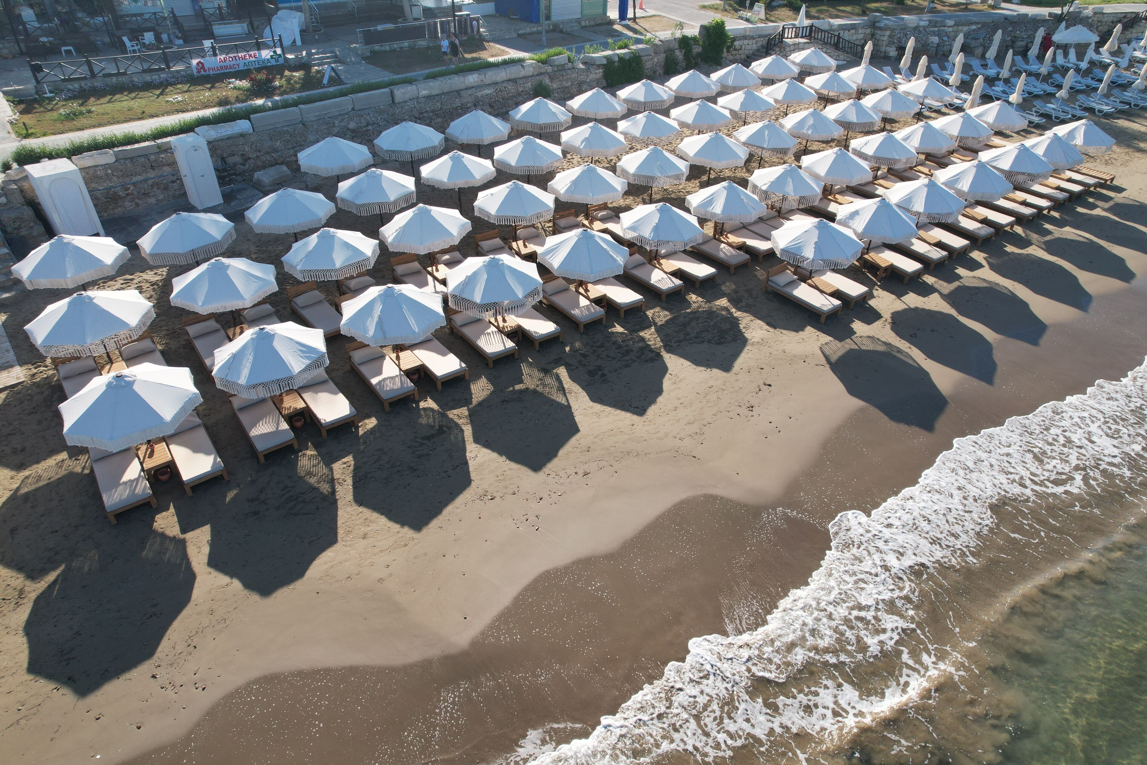 A beach with rows of sun loungers and white umbrellas.