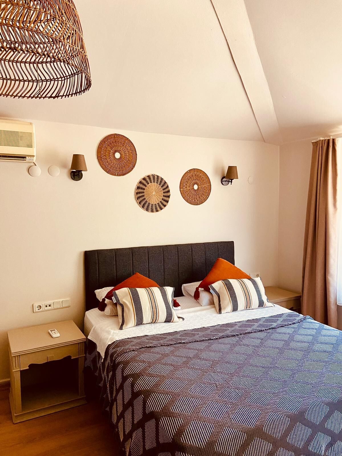 A neatly arranged bedroom with a bed, bedside tables, and decorative wall hangings.