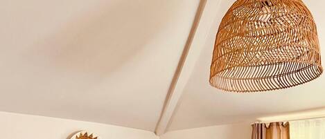 A dining area with a wooden table and chairs, a woven pendant light, and three woven wall decorations.