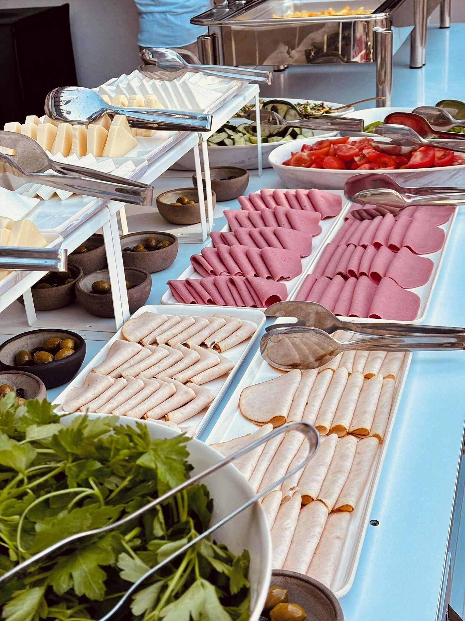 A buffet with various food items including meats, vegetables, and condiments.