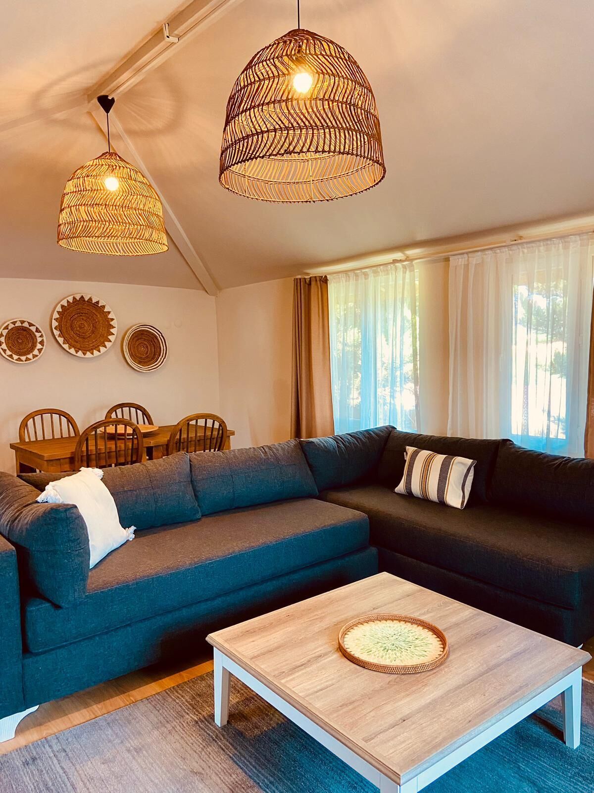 A modern living room with a sectional sofa, a coffee table, and a dining area with chairs and a table.
