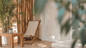 A wooden deck with a table and a chair, surrounded by potted plants.