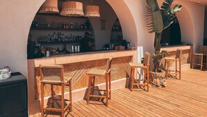 A bar area with wooden chairs and a counter displaying various bottles. - Kalia Beach Hotel Side  (Manavgat)