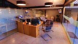 Una zona de recepción moderna con un mostrador de madera, computadora y asientos.
