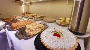 Una mesa de buffet con diversos postres y un dispensador de agua.
