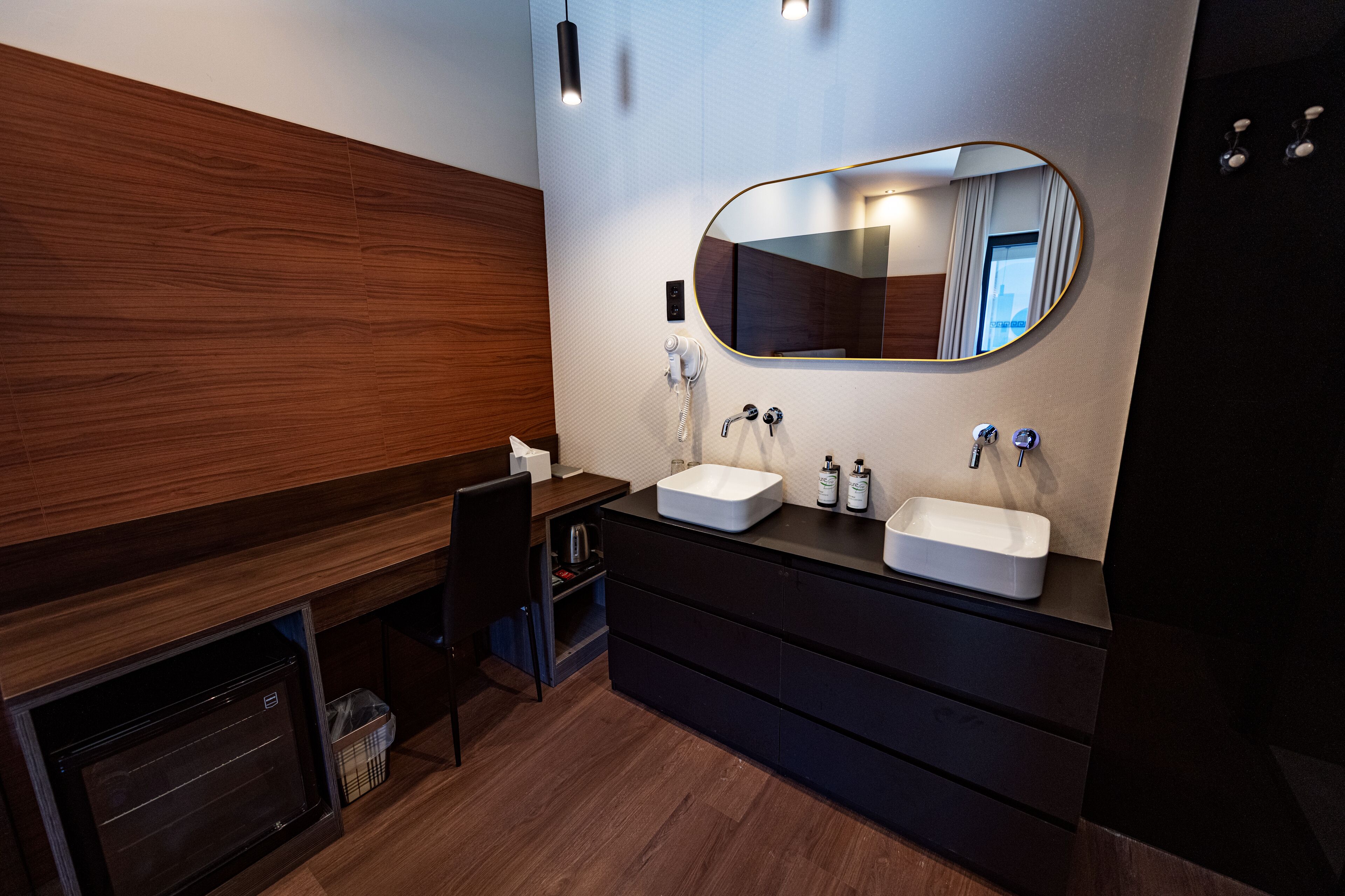 Un baño moderno con dos lavamanos, un espejo y calefacción integrada.