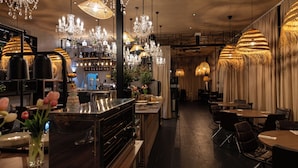 A restaurant interior with chandeliers, tables, and a bar area. - Rubens Hotels & SPA (Vila Nova de Gaia)