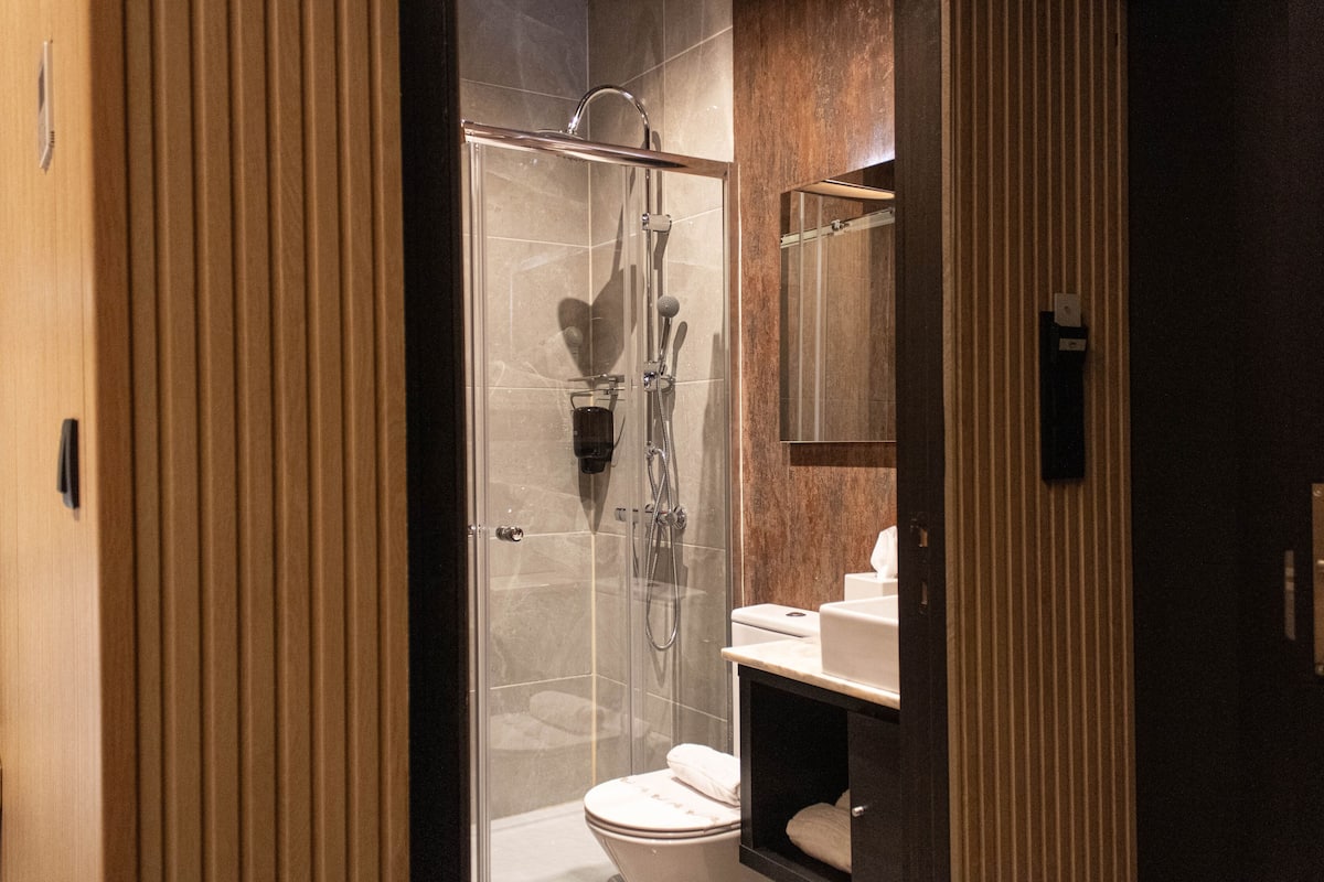 Ein modernes Badezimmer mit einer Duschkabine, einer Toilette und einem Waschtisch mit Spiegel.