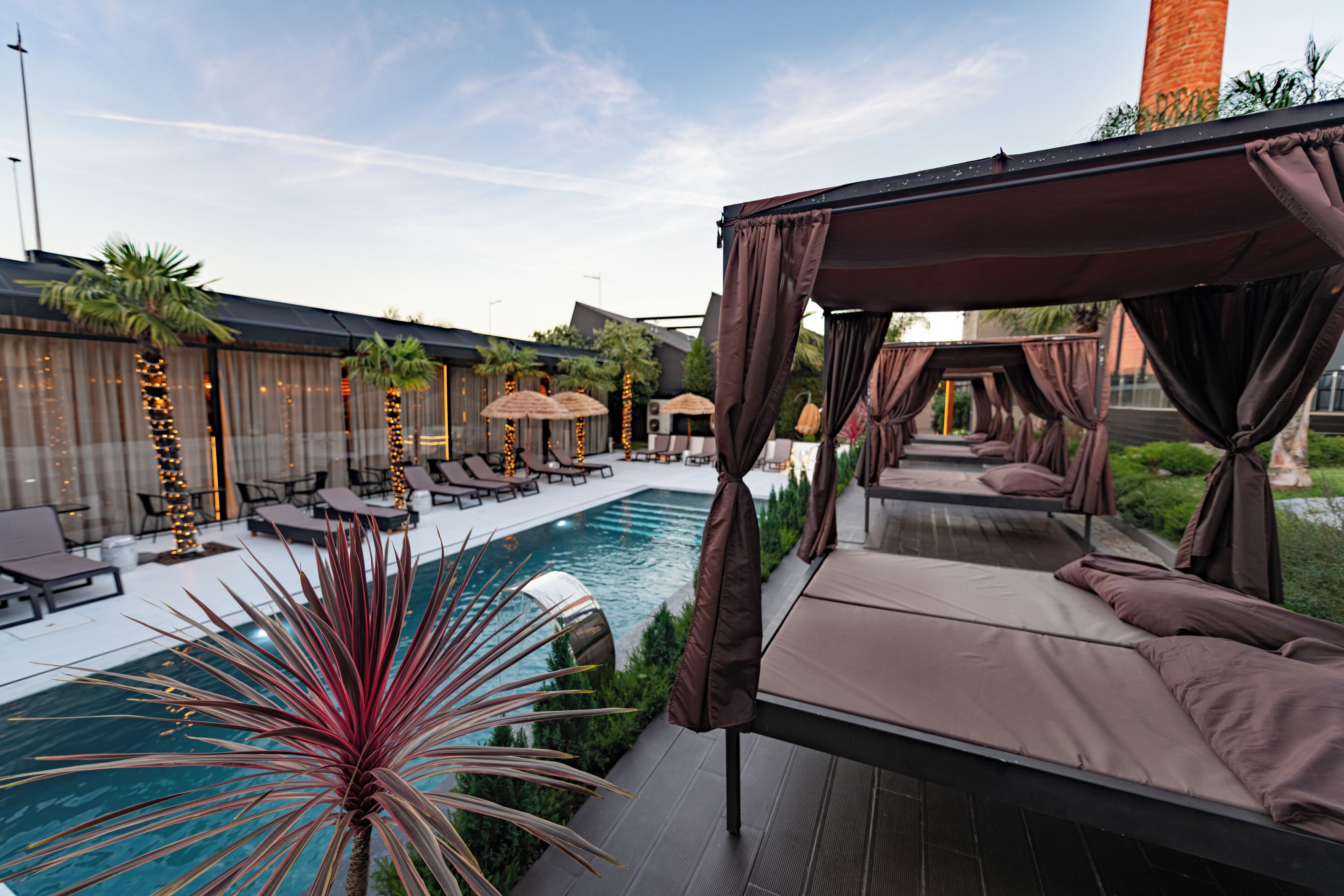 A poolside area with a canopy bed, lounge chairs, and a swimming pool.