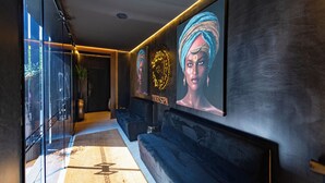 A hallway with a glass door, a dark wall with a clock, and a spa sign. - Rubens Hotels & SPA (Vila Nova de Gaia)
