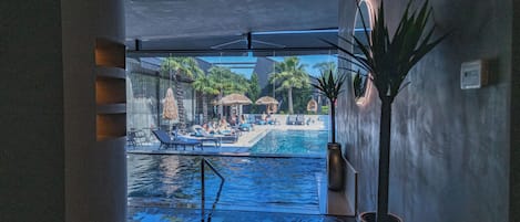 Piscine couverte, piscine extérieure, parasols de plage, chaises longues
