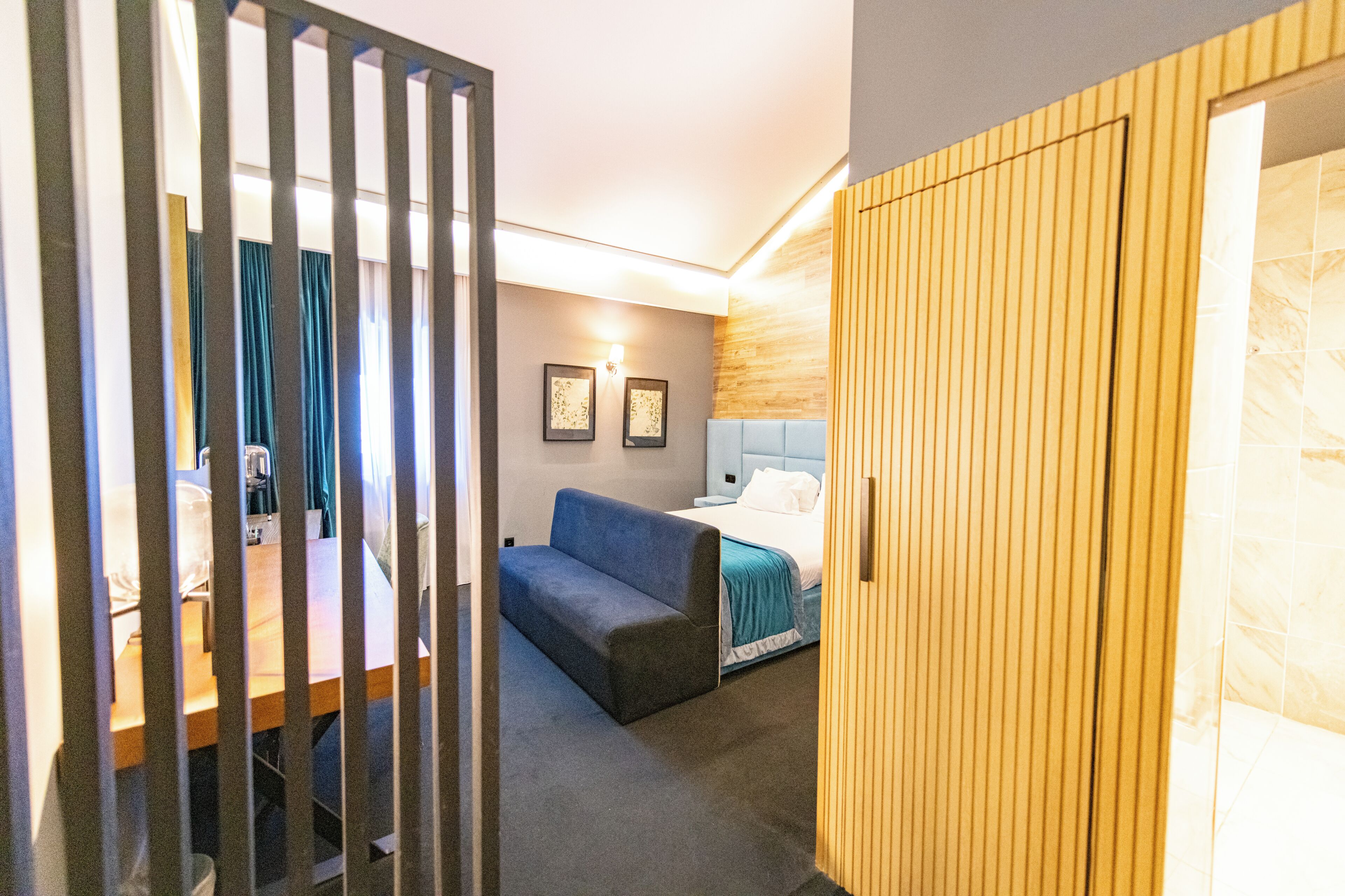 Une chambre d’hôtel comprenant un lit, un canapé, une armoire en bois et un bureau avec une chaise.