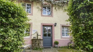 A building with a stone well, a door, and a sign that reads "Korbblume." - Nengshof (Wissmannsdorf)