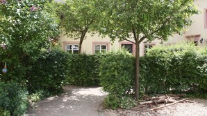 A garden pathway leading to a building with a beige facade and pink trim. - Nengshof (Wissmannsdorf)