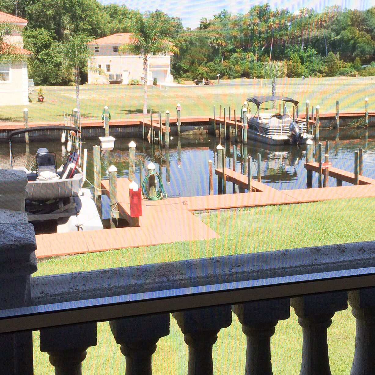A marina with boats docked, a grassy area, and a building in the background.