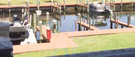 A marina with boats docked, a grassy area, and a building in the background.