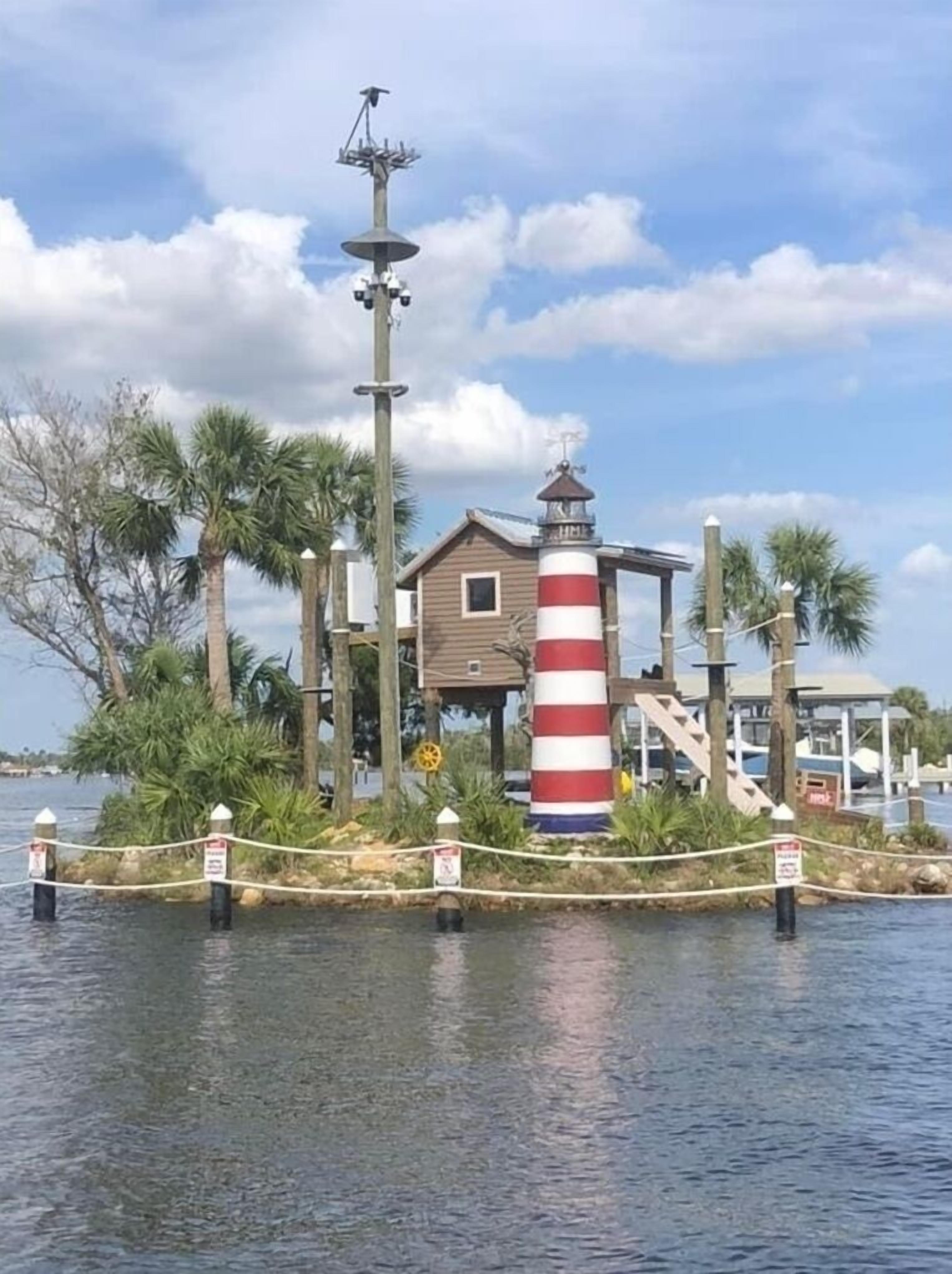 Un faro con una torre a rayas rojas y blancas, un pequeño edificio de madera y un veleta en la parte superior.